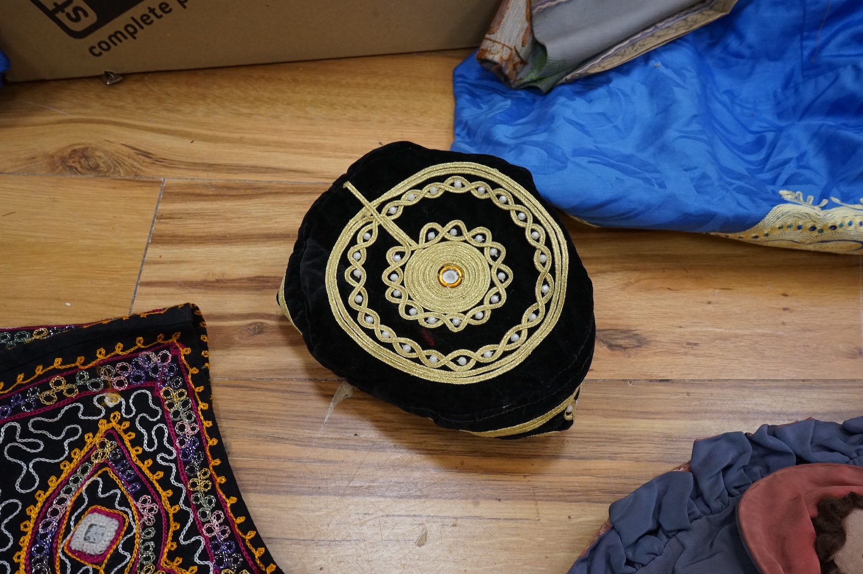 A quantity of mostly 20th century Middle Eastern and Indian woven and printed textiles and a peacock feather fan (2 boxes).